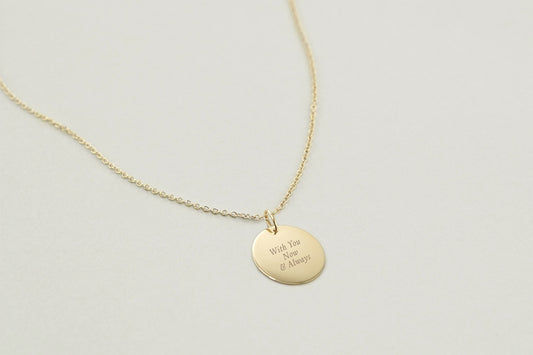Gold necklace with a round pendant on a light gray background