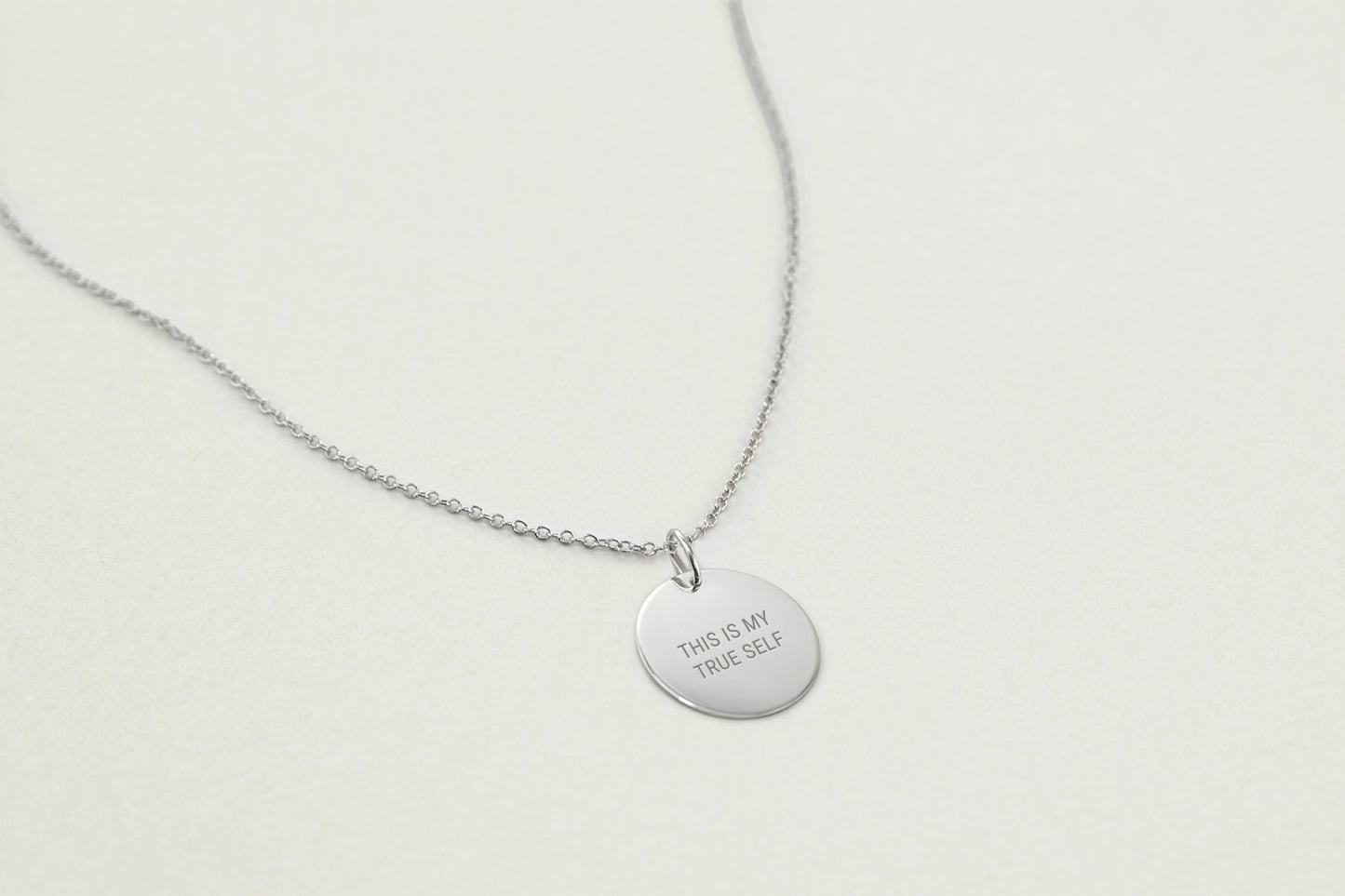 Silver necklace with a round pendant on a light gray background