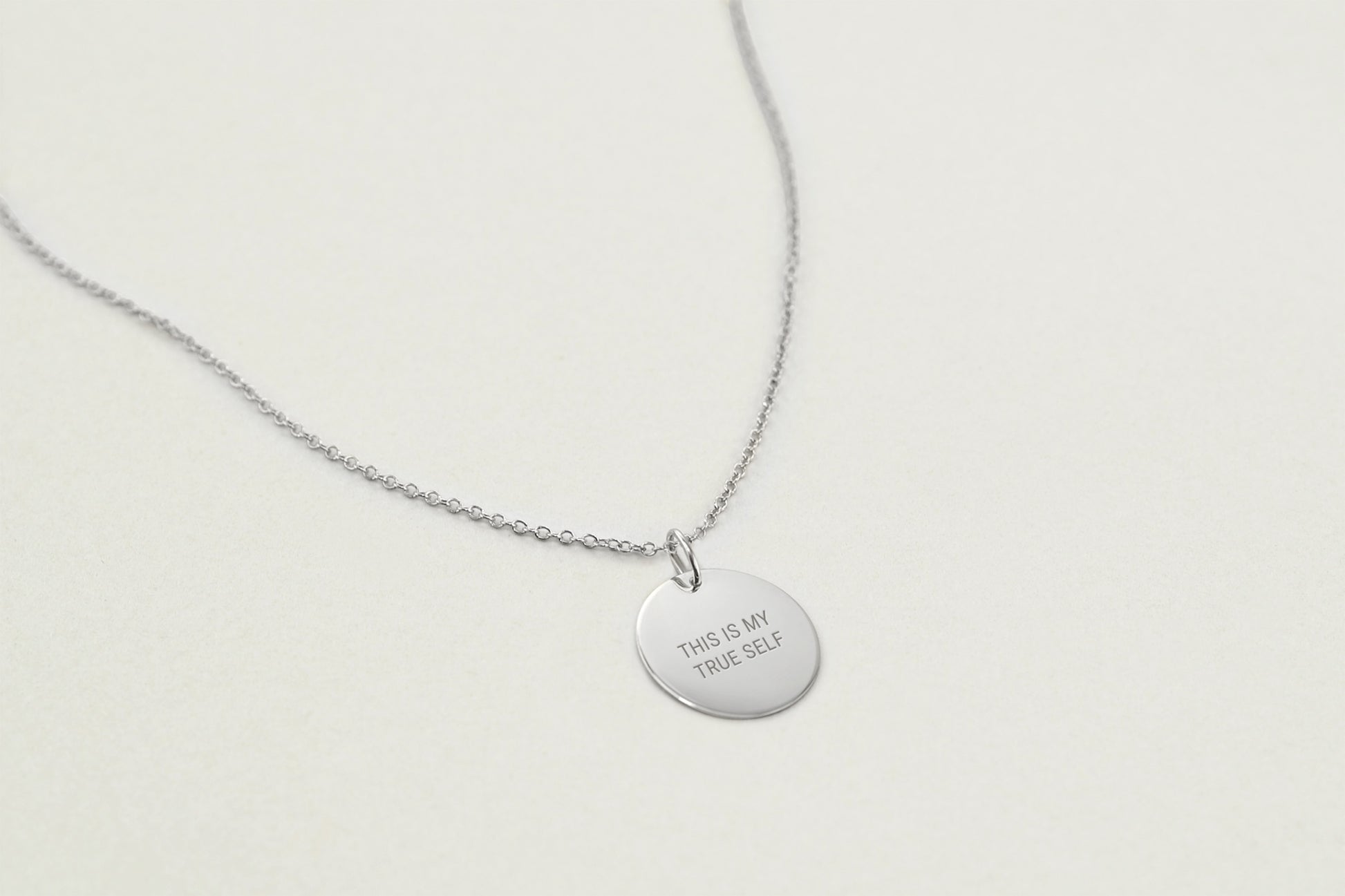 Silver necklace with a round pendant on a light gray background