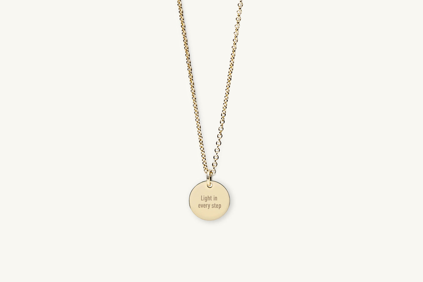 Gold necklace with a round pendant on a white background