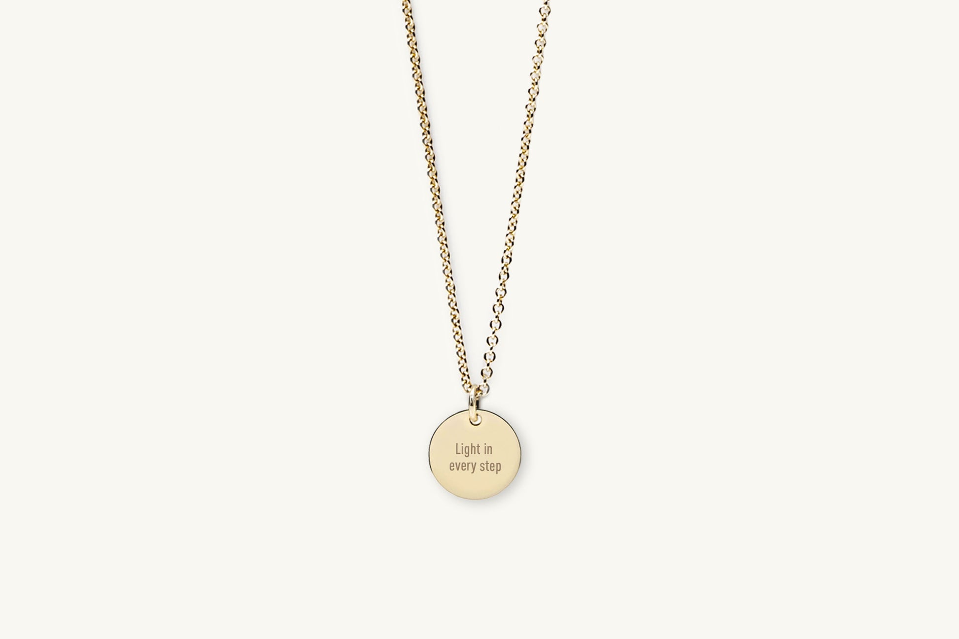 Gold necklace with a round pendant on a white background