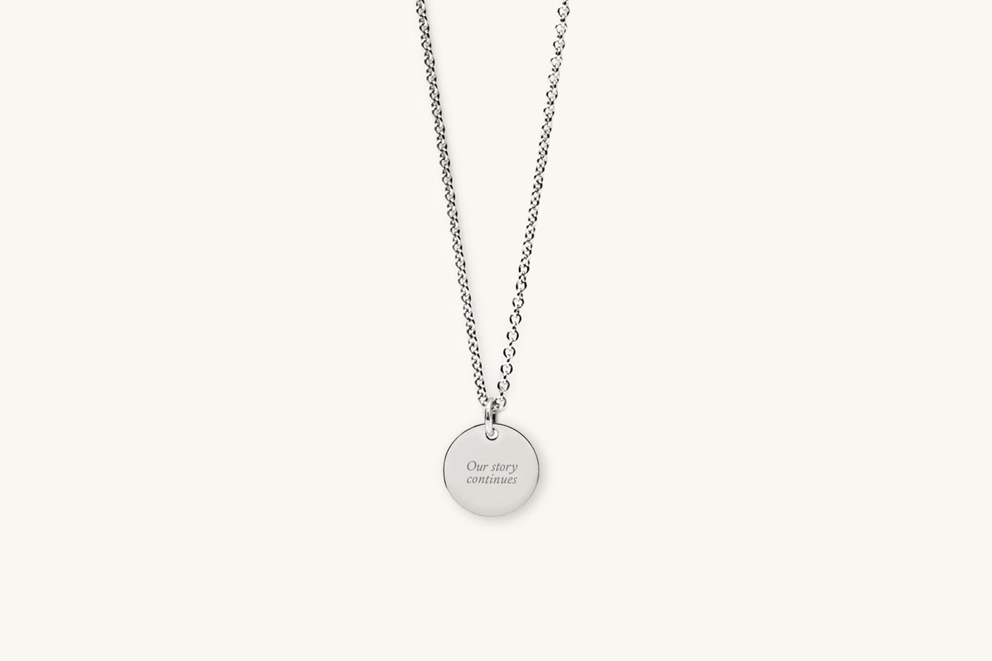 Silver necklace with message engraved on a round pendant on a white background