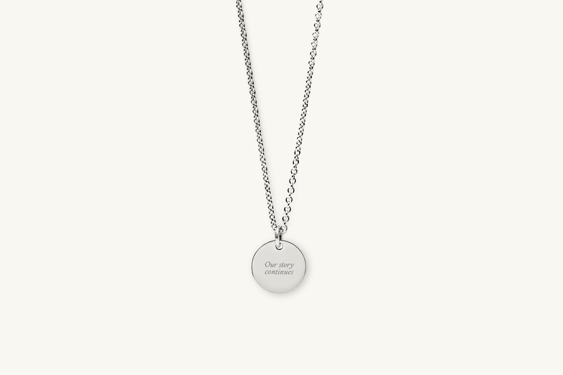 Silver necklace with message engraved on a round pendant on a white background