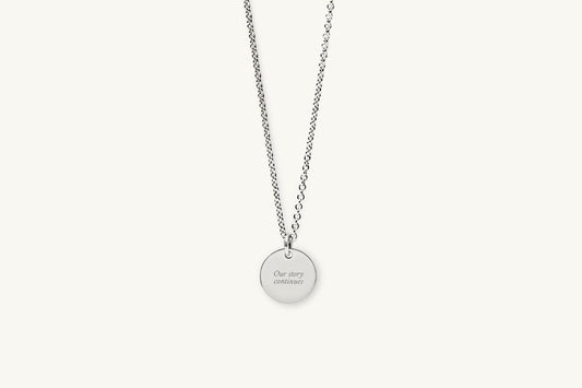 Silver necklace with message engraved on a round pendant on a white background