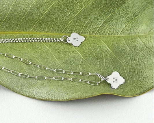Silver necklace with clover-shaped charms on a green leaf